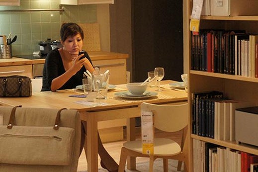 A woman sits at a model room in an IKEA Store.